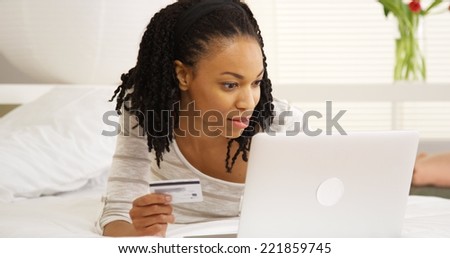 Happy black woman smiling with laptop and credit card