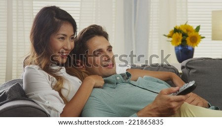 Japanese woman and her boyfriend watching tv and laughing