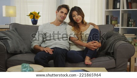 Japanese mixed couple sitting on couch smiling