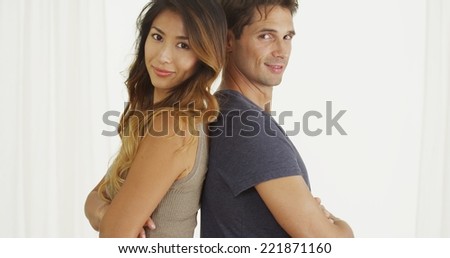 Mixed race couple standing back to back