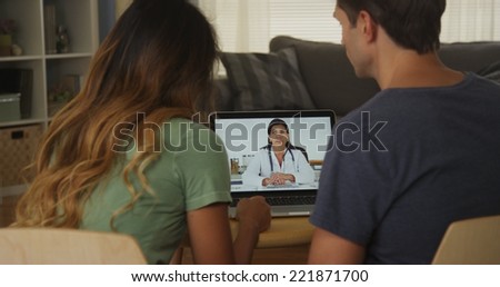 Interracial couple talking with doctor on laptop