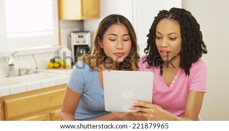 Asian and African American friends using tablet computer in kitchen