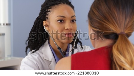 Close up of African American doctor listening to heart and lungs of patient