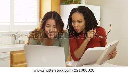 Adult women college students reading book and using laptop computer to study