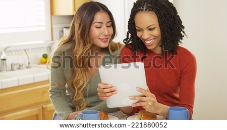 Two women best friends eating breakfast and using tablet computer