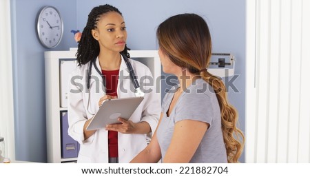 African American doctor with tablet computer talking to Asian patient