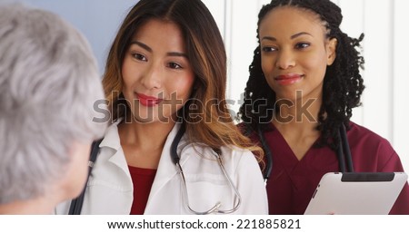 Asian woman physician and black nurse with elderly patient
