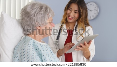 Japanese doctor showing elderly patient information on tablet computer