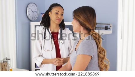 African American doctor with tablet computer talking to Asian patient
