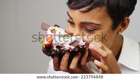 Black woman making a mess eating a huge fancy dessert