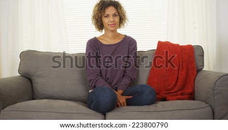 Black woman sitting on couch looking at camera