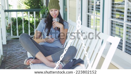Young woman texting and sitting on porch