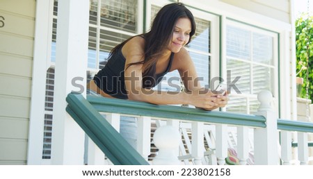 Hispanic woman leaning on rail texting