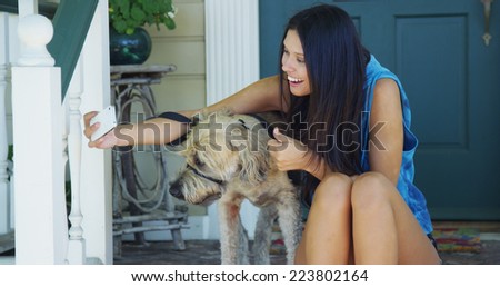 Mixed race woman sitting on porch taking pictures with dog