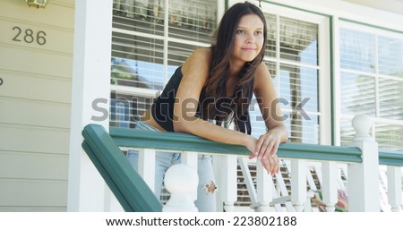 Hispanic woman leaning on rail smiling