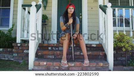 Mixed race woman sitting on porch with skateboard