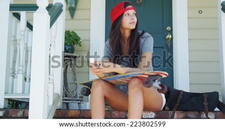 Skatergirl sitting on porch texting