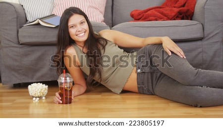 Hispanic woman lying on living room floor with iced tea