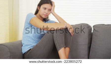 Mixed race woman sitting on couch thinking