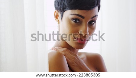 Beautiful topless woman hugging herself and standing by window