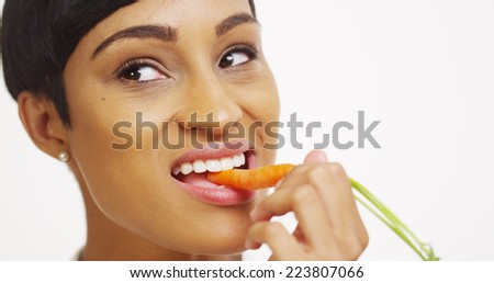 Close up of black woman eating carrot on white background