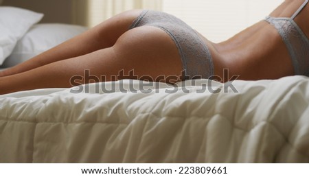 Sexy hispanic woman lying on bed in lingerie