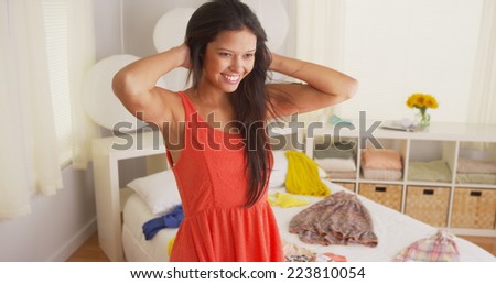 Young Hispanic woman trying on clothes in bedroom