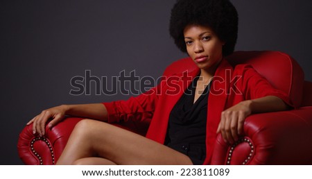 Independent black woman sitting in red chair