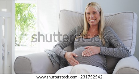 Beautiful pregnant woman sitting on rocking chair in nursery