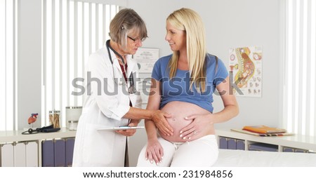 Happy doctor touching pregnant woman\'s belly