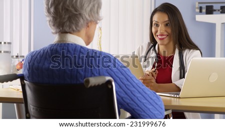 Hispanic woman doctor talking with elderly patient