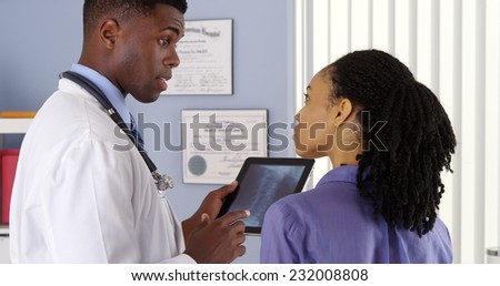 African American woman with neck pain talking to doctor about x ray on tablet