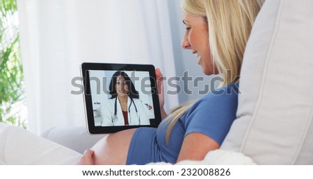 Pregnant woman talking to her doctor on tablet