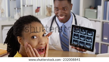Black physician using tablet to show ultrasound to patient at desk