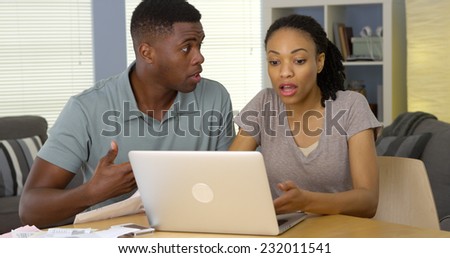 Upset young Black couple arguing over bills and finances with laptop