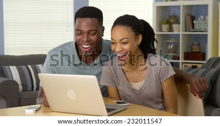 Young black couple watching funny video on laptop