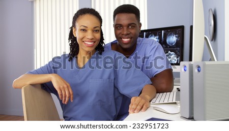 Two Black nurses in nurses station sitting at computer