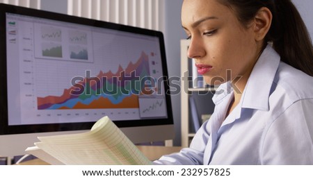 Mexican businesswoman writing notes by computer