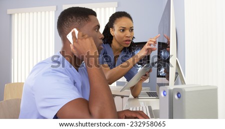 Two Black medical specialists using computer to review information together