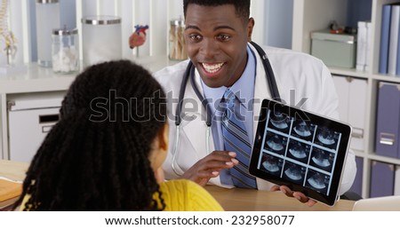 African American gynecologist using tablet to show ultrasound to patient at desk