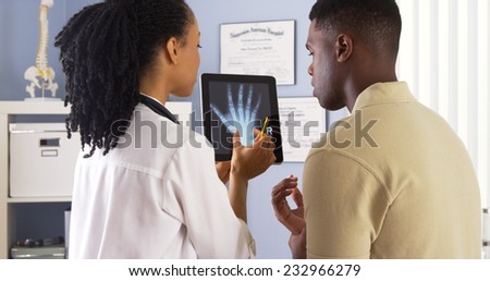 Black female doctor sharing hand x ray with patient on tablet