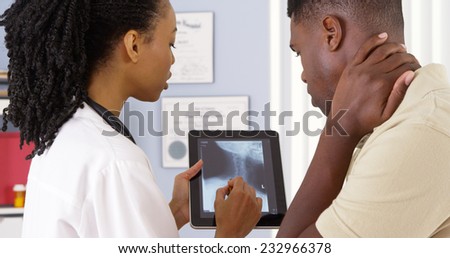 Patient with neck pain talking to female doctor about x ray on tablet