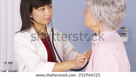 Asian doctor listening to elderly patient\'s heart
