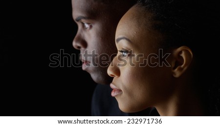 Dramatic side view of two young African American people on black background