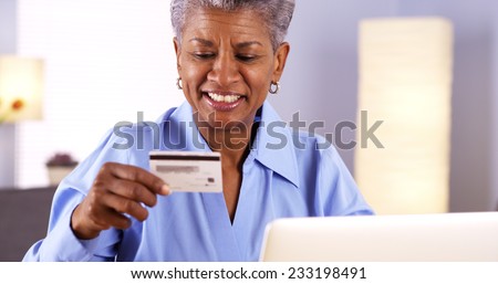 Happy Mature Black woman typing in card information