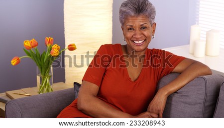 Cheerful African grandmother sitting on couch