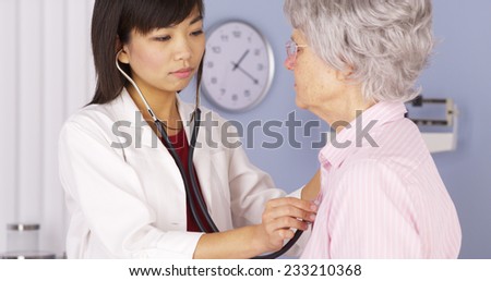 Chinese doctor listening to elderly patient\'s heart