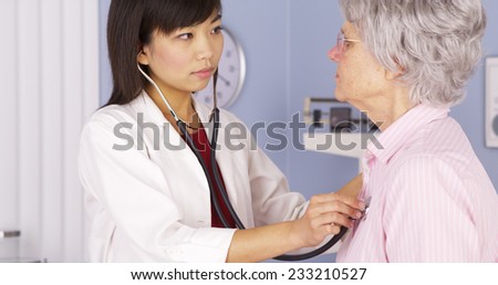 Chinese doctor listening to elderly patient\'s heart