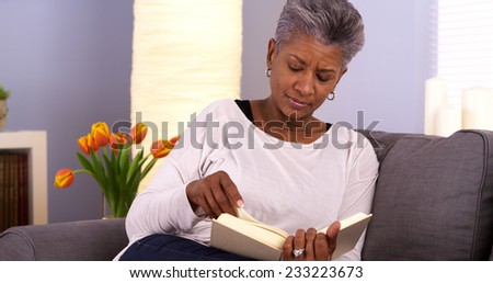 Mature African woman reading book on couch