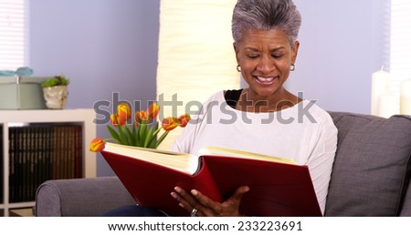 Happy senior black woman looking though photo album
